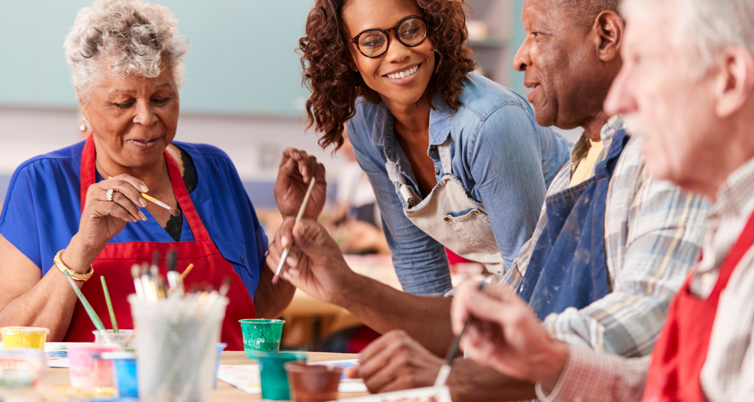 Older adults painting together during a community art class with instructor support