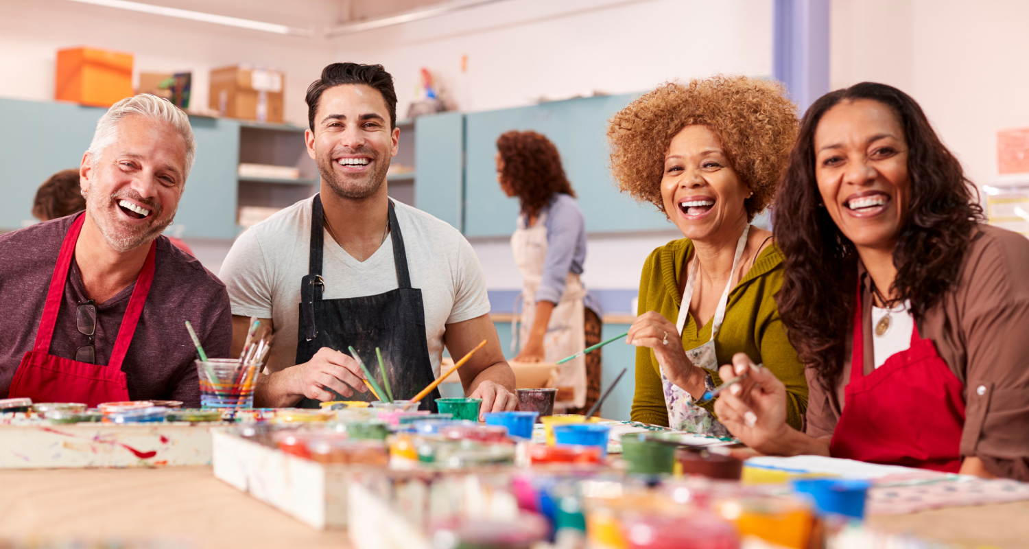 Group of adults painting and smiling during a creative art class
